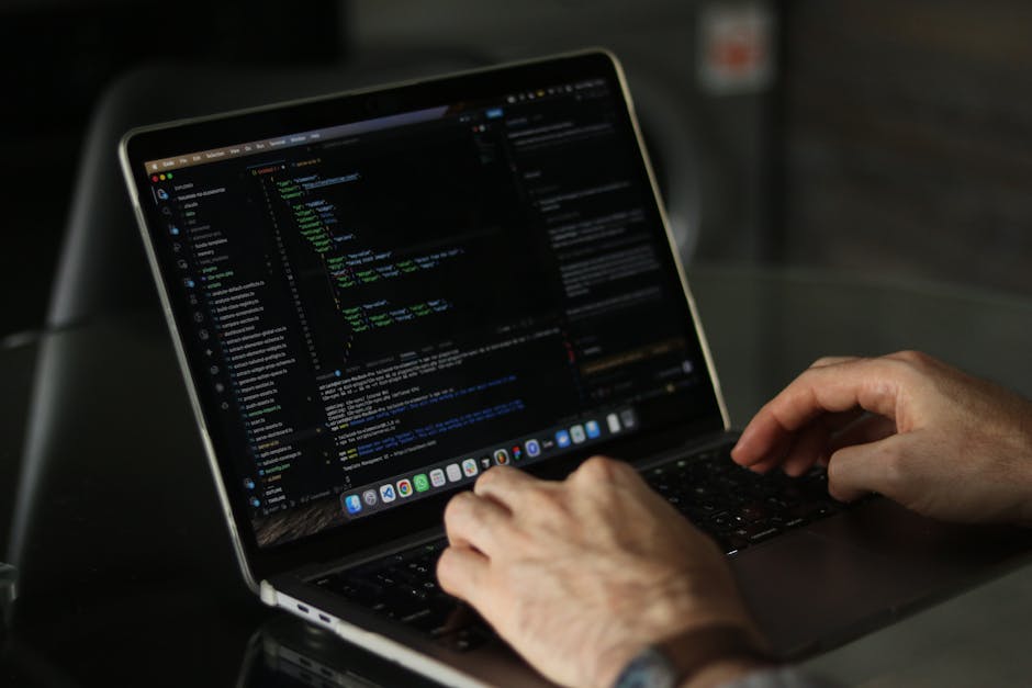 A digital screen displays lines of colourful programming code on a dark background, with syntax highlighting featuring green, yellow, white, red, and orange text. The code includes snippets related to